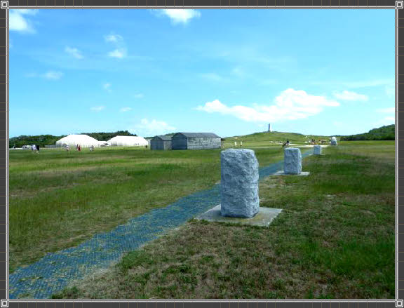 Felssteine symbolisieren die Reichweite, im Hintergrund das Wright Brothers Monument